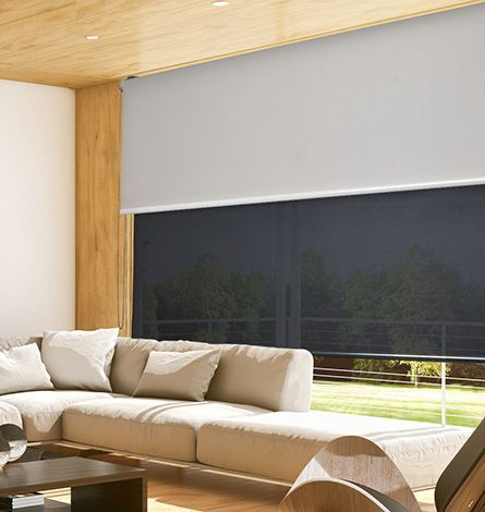 Beige Sofa in Modern Living Room With Drawn Grey Roller Shade Over Dark Window — GV Blinds in Shepparton, VIC