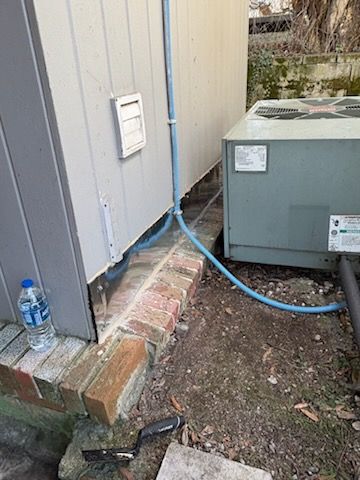 A bottle of water is sitting next to a building with a hose attached to it. | Waterproofing Birmingham, AL