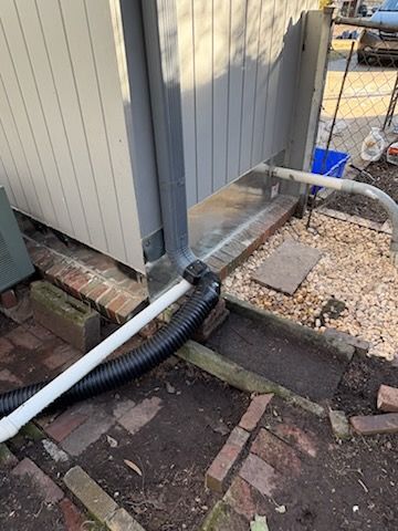 A vacuum hose is attached to a pipe outside of a building. | Waterproofing Birmingham, AL