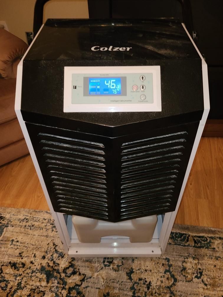 A colzer humidifier is sitting on a rug in a living room