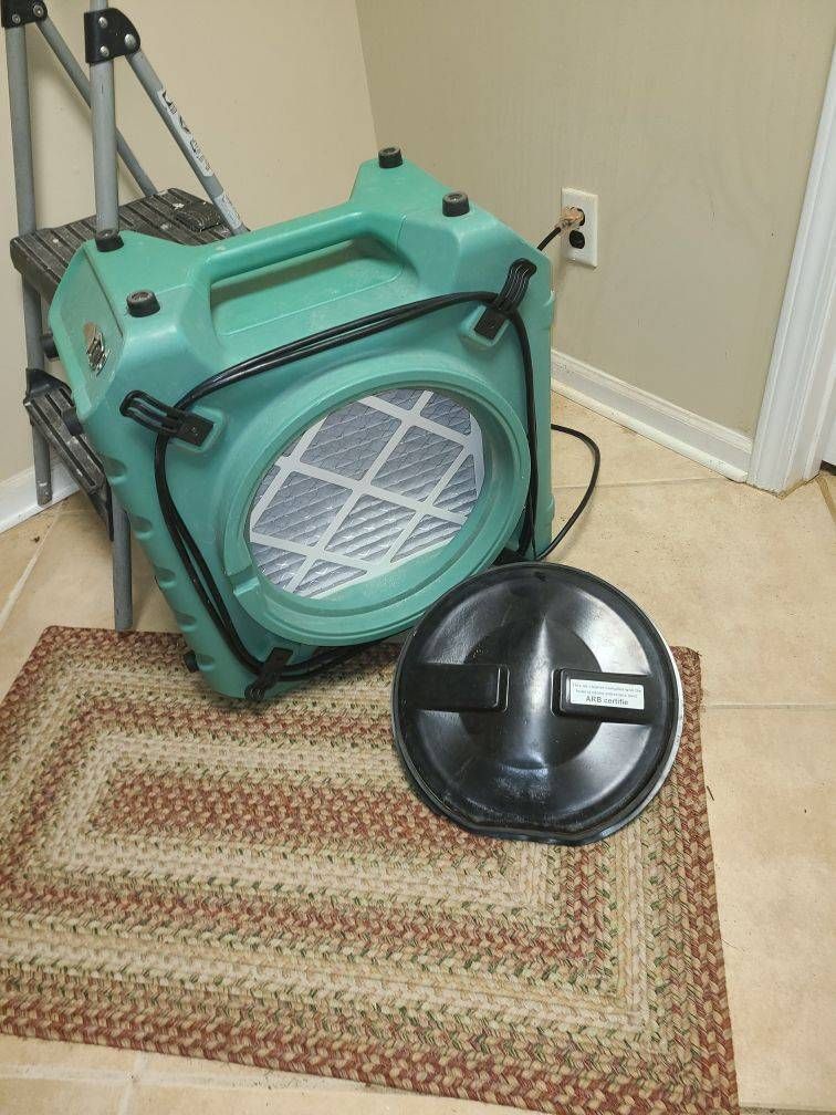 A green fan is sitting on a rug in a room.