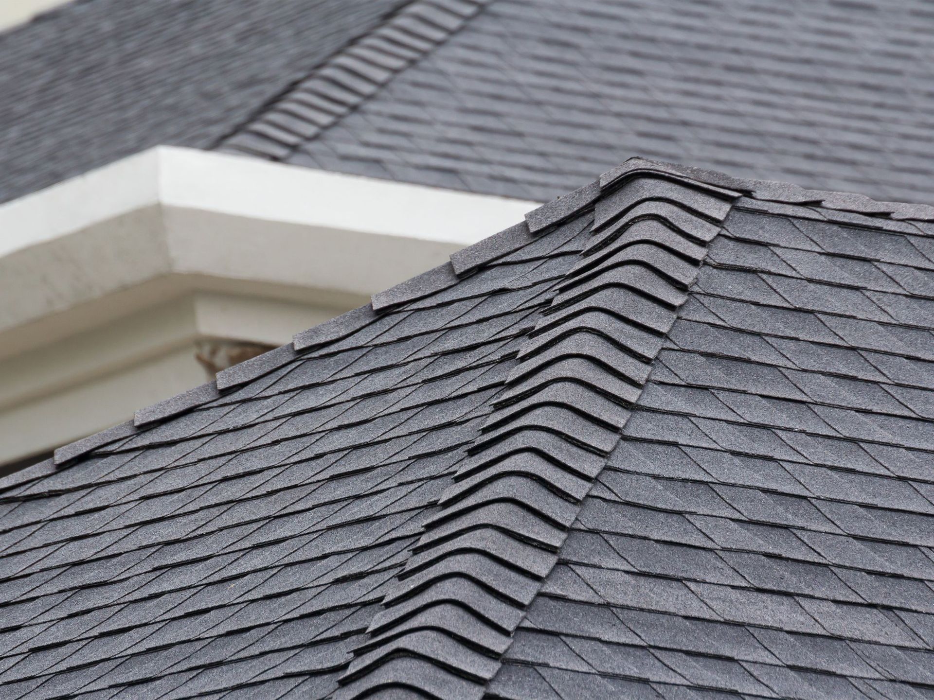 A close up of a roof with shingles and a window.