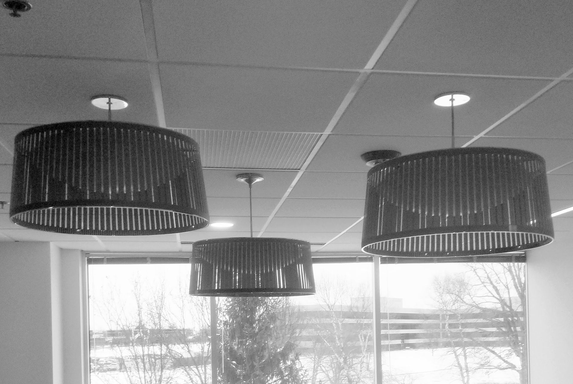 A black and white photo of three lamps hanging from the ceiling in a room.