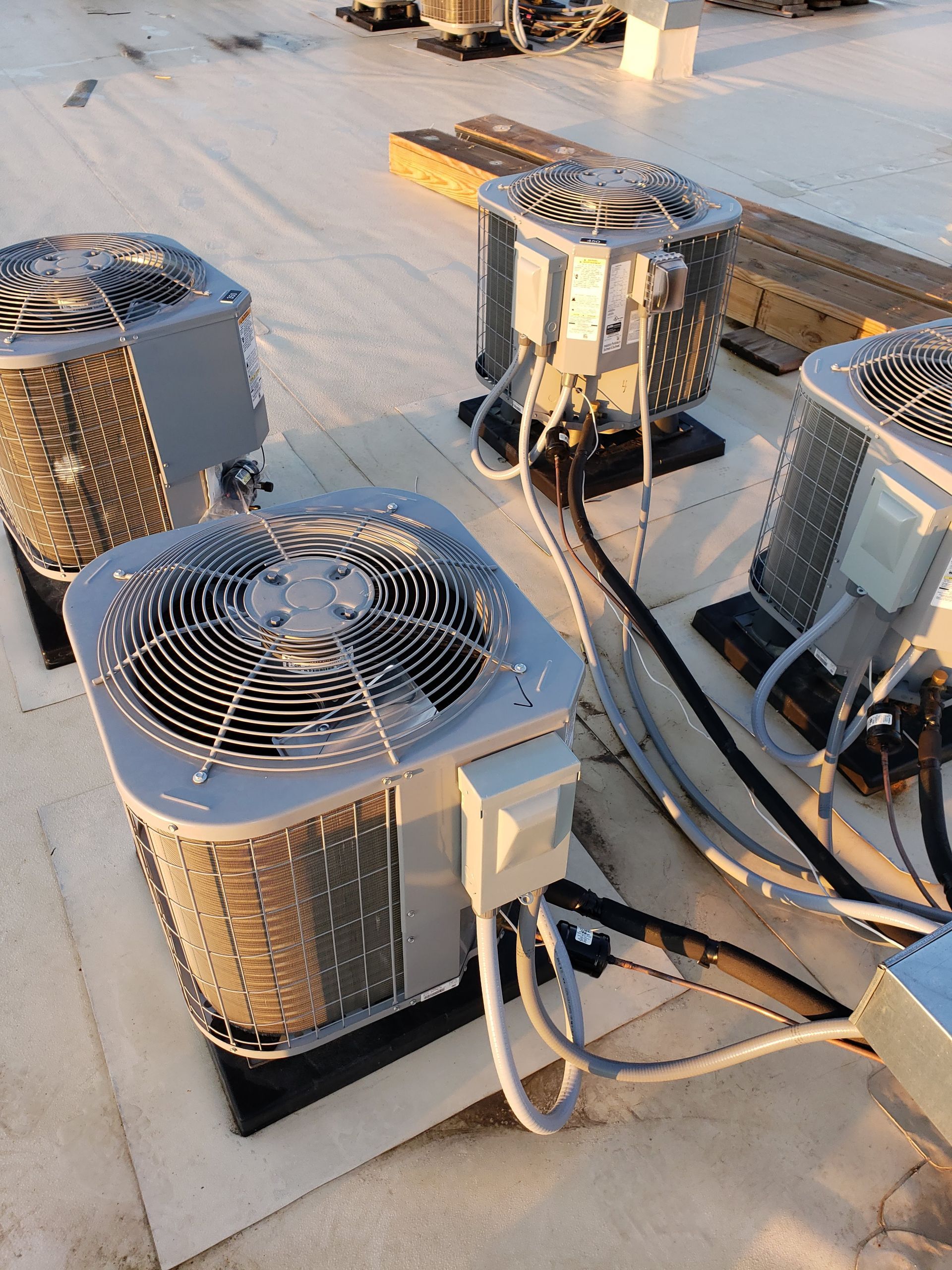 Three air conditioners are sitting on top of a roof.
