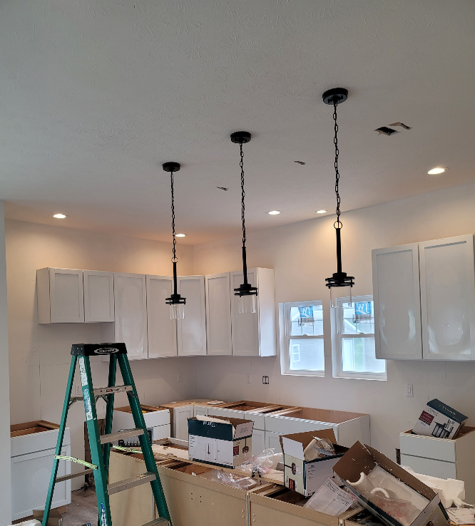 A kitchen under construction with white cabinets and a green ladder.