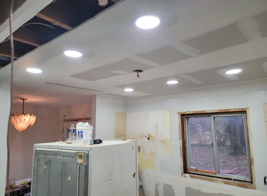 A kitchen under construction with a refrigerator and a window.