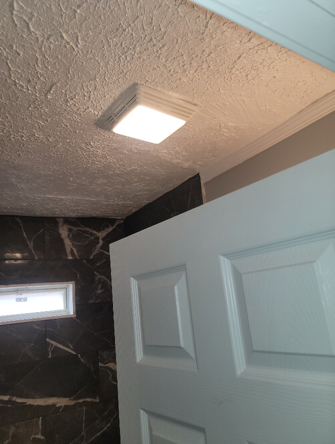 A white door with a light on the ceiling above it