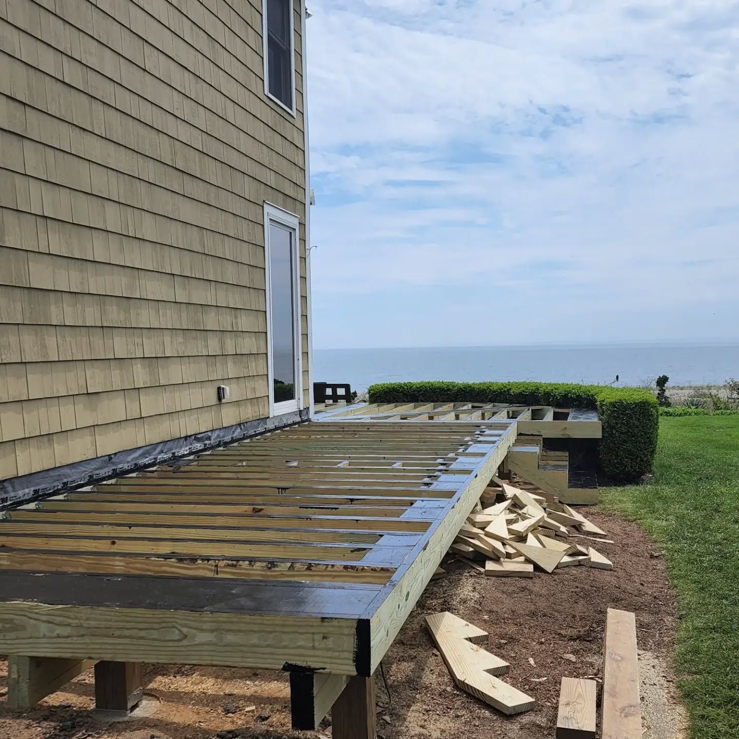 A wooden deck is being built in front of a house with a view of the ocean.
