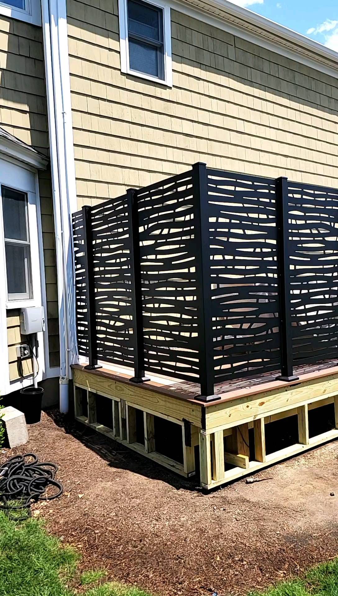A house with a deck and a fence in front of it.