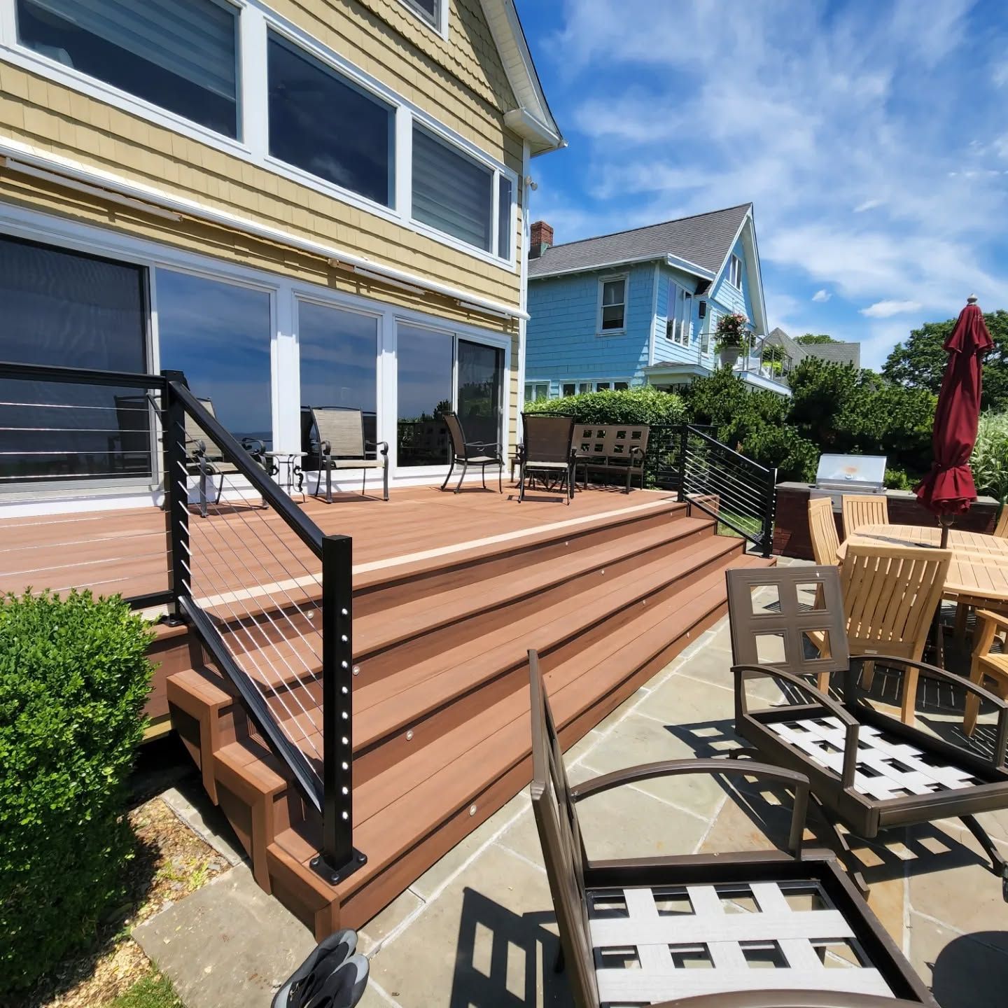 A wooden deck with stairs and chairs in front of a house