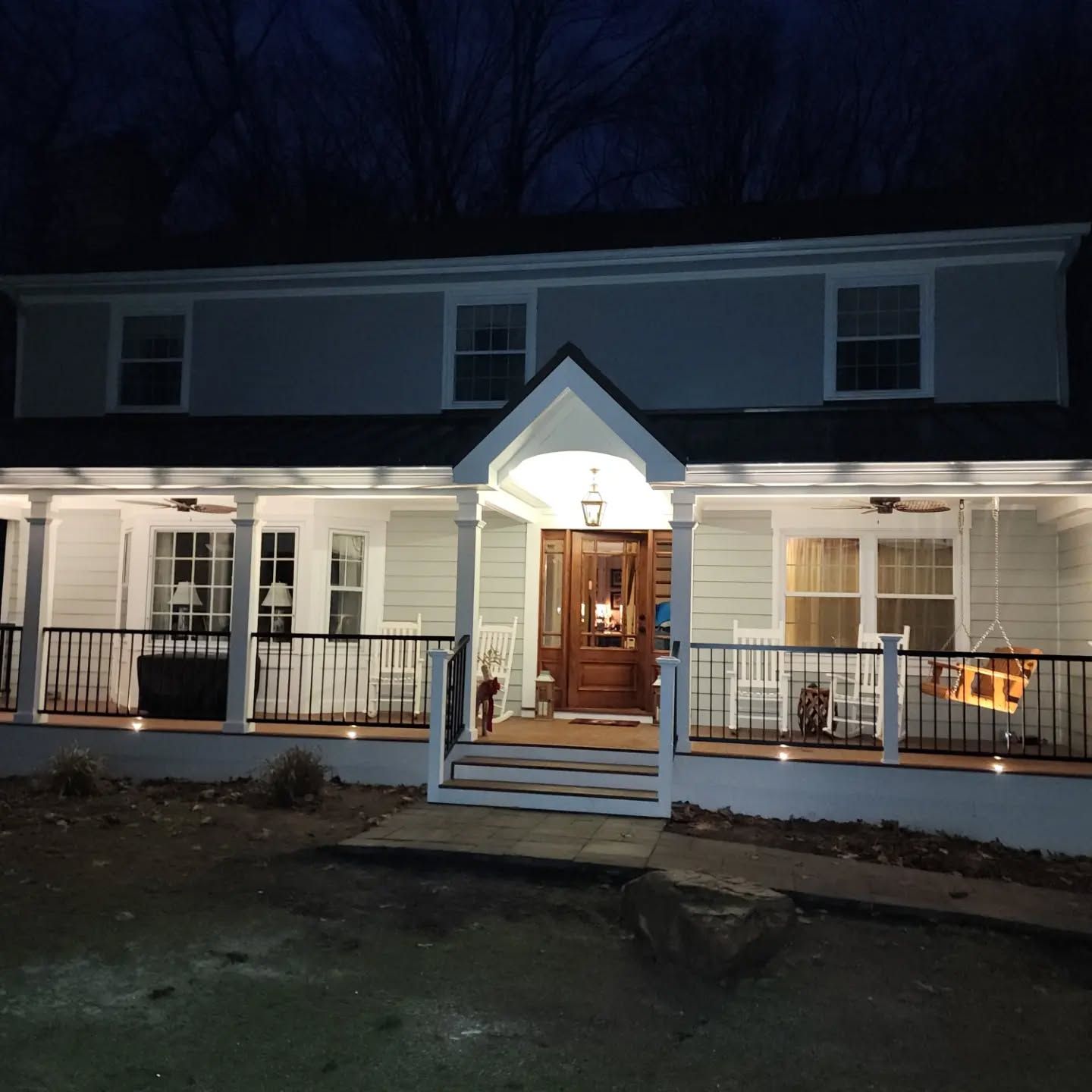 A house with a porch and stairs is lit up at night