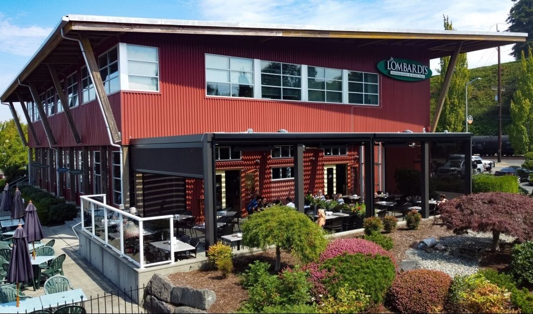 An aerial view of a large red building with tables and chairs in front of it.