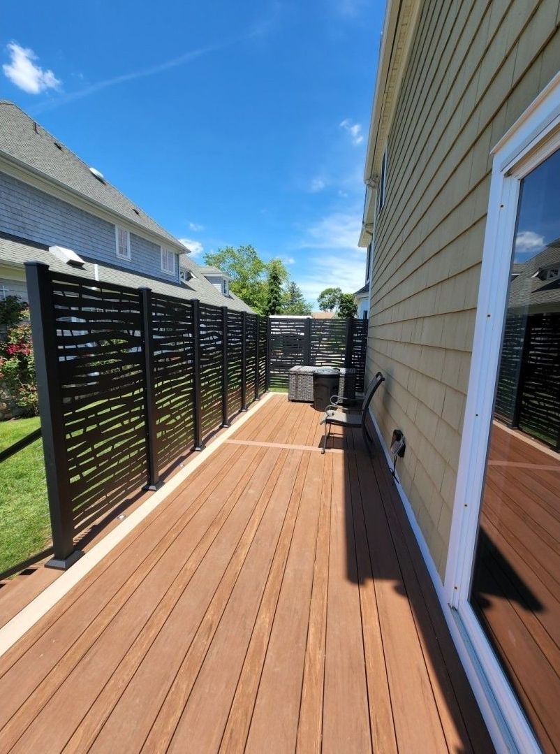 A wooden deck with a fence in the backyard of a house