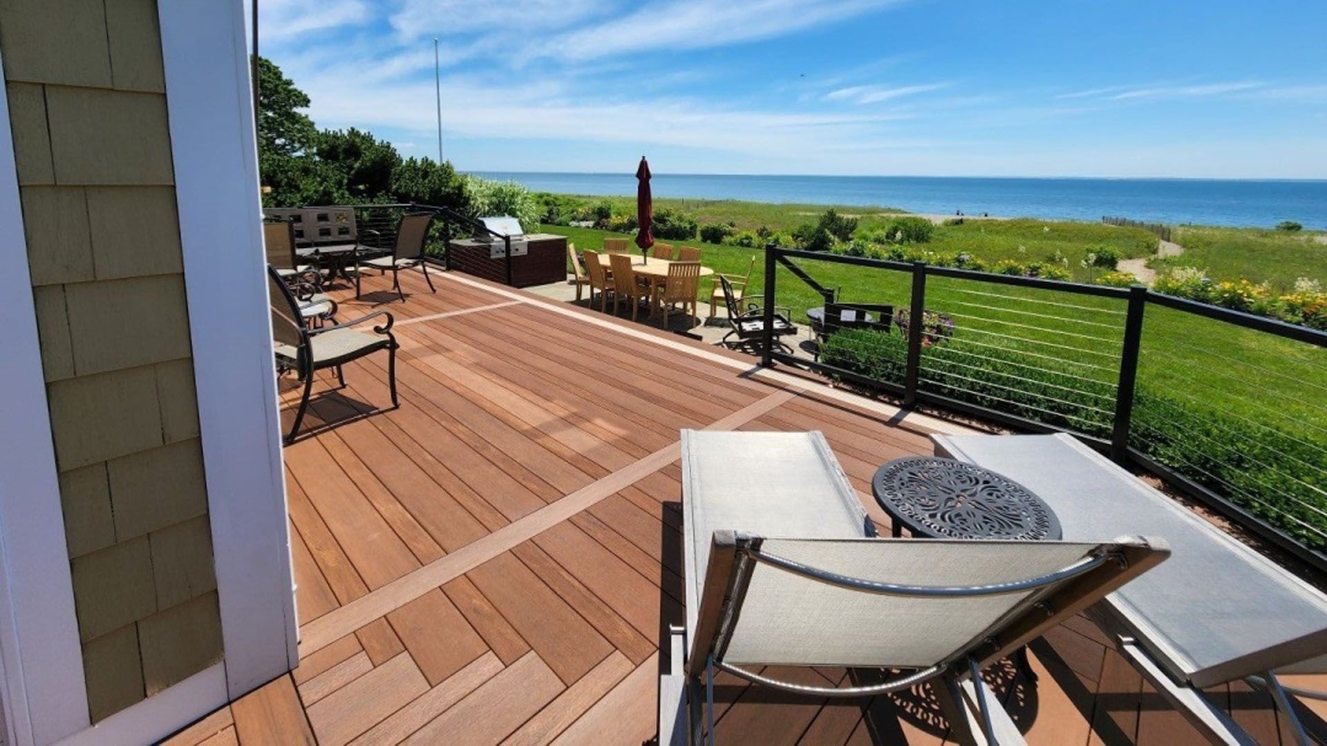 A deck with chairs and a table overlooking the ocean