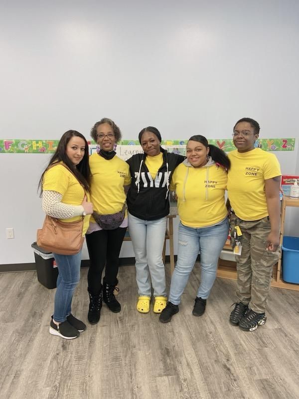 Five people in yellow shirts and casual clothes pose together.