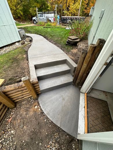 A concrete walkway with stairs leading up to a house.