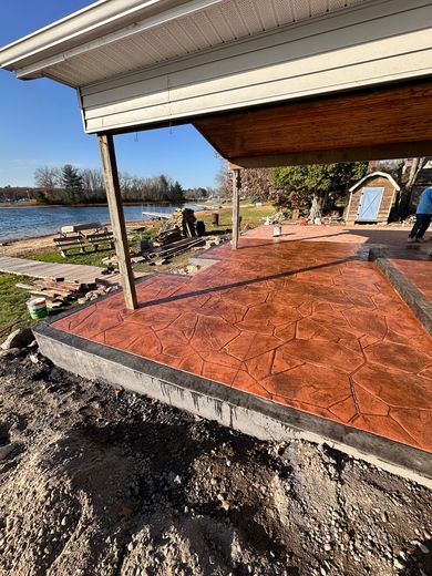 A concrete patio is being built in front of a house next to a body of water.