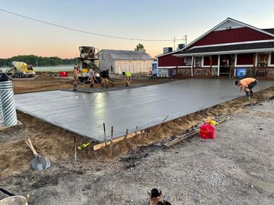 A group of people are working on a concrete driveway in front of a house.