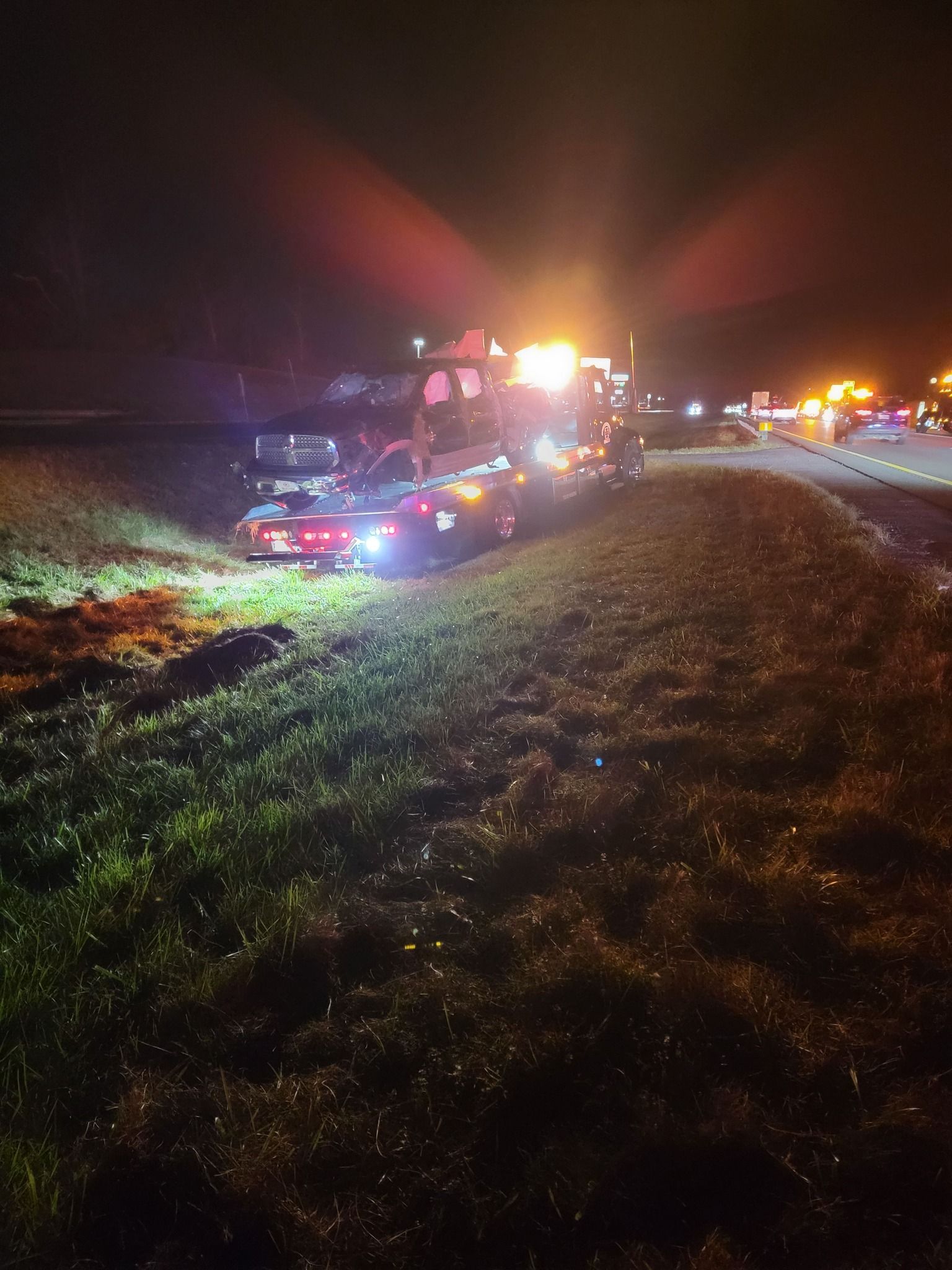 Nighttime scene of cars involved in an accident with tow trucks and emergency lights.