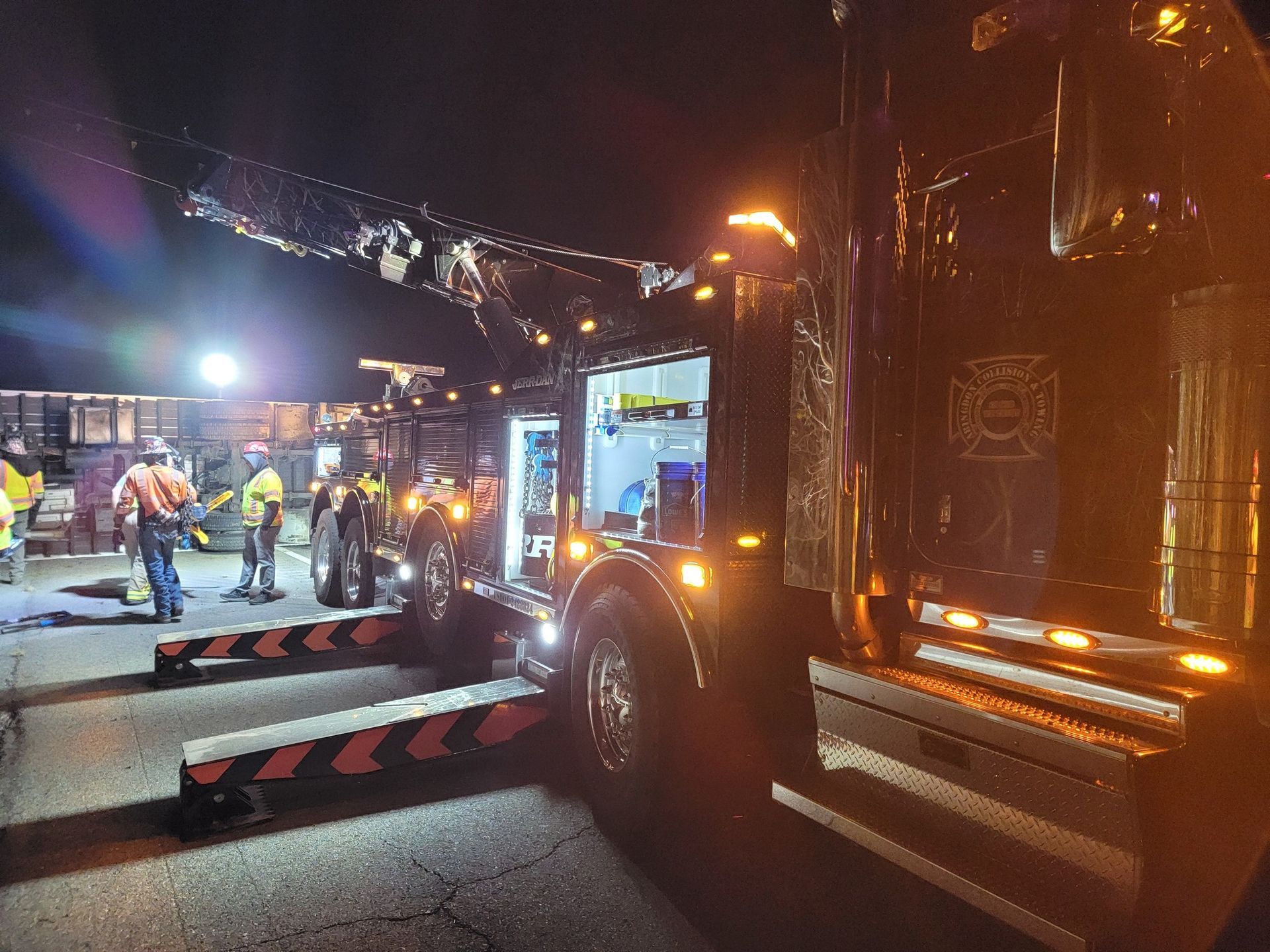 Fire truck at night with responders; equipment deployed. Scene is illuminated.