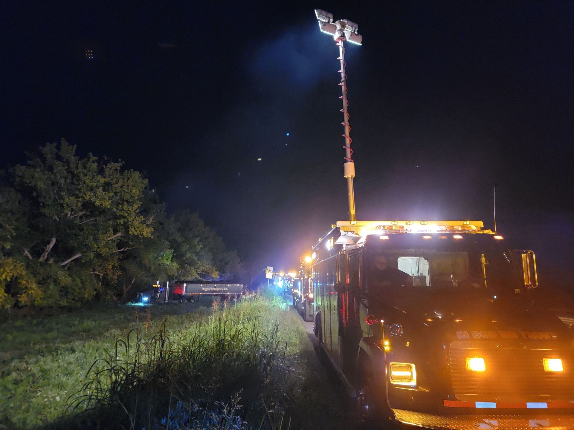 Night scene: Emergency response vehicles with lights illuminate a roadside, potentially after an incident.