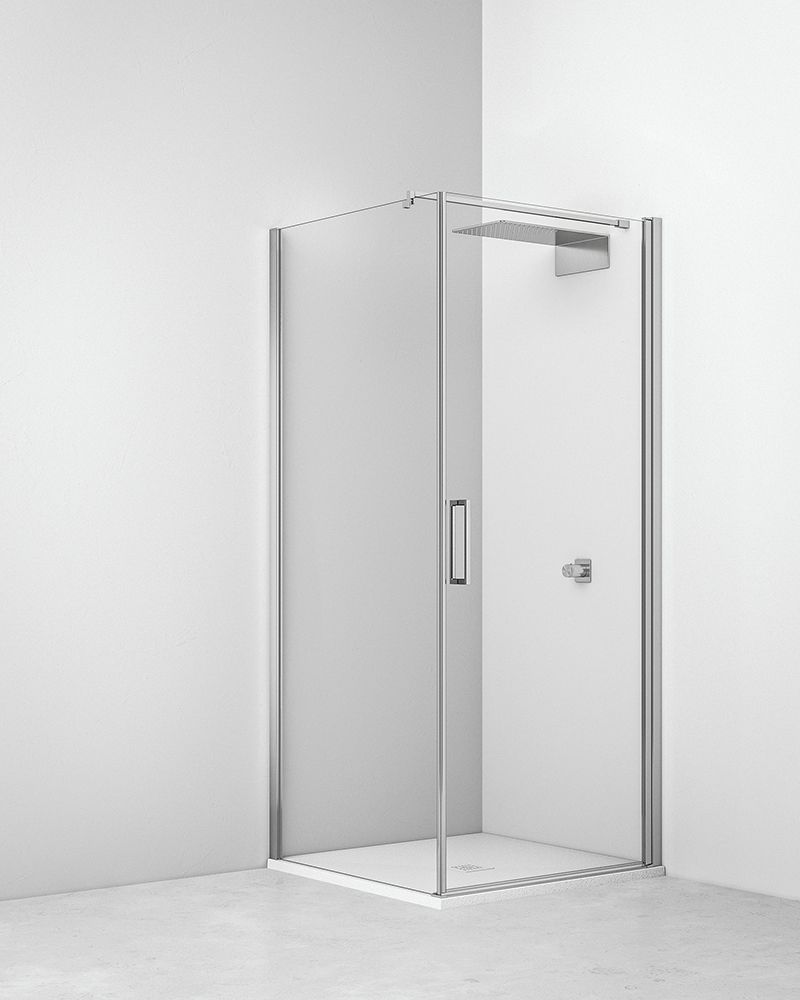 Box doccia angolare in vetro trasparente con accessori cromati in un bagno bianco.