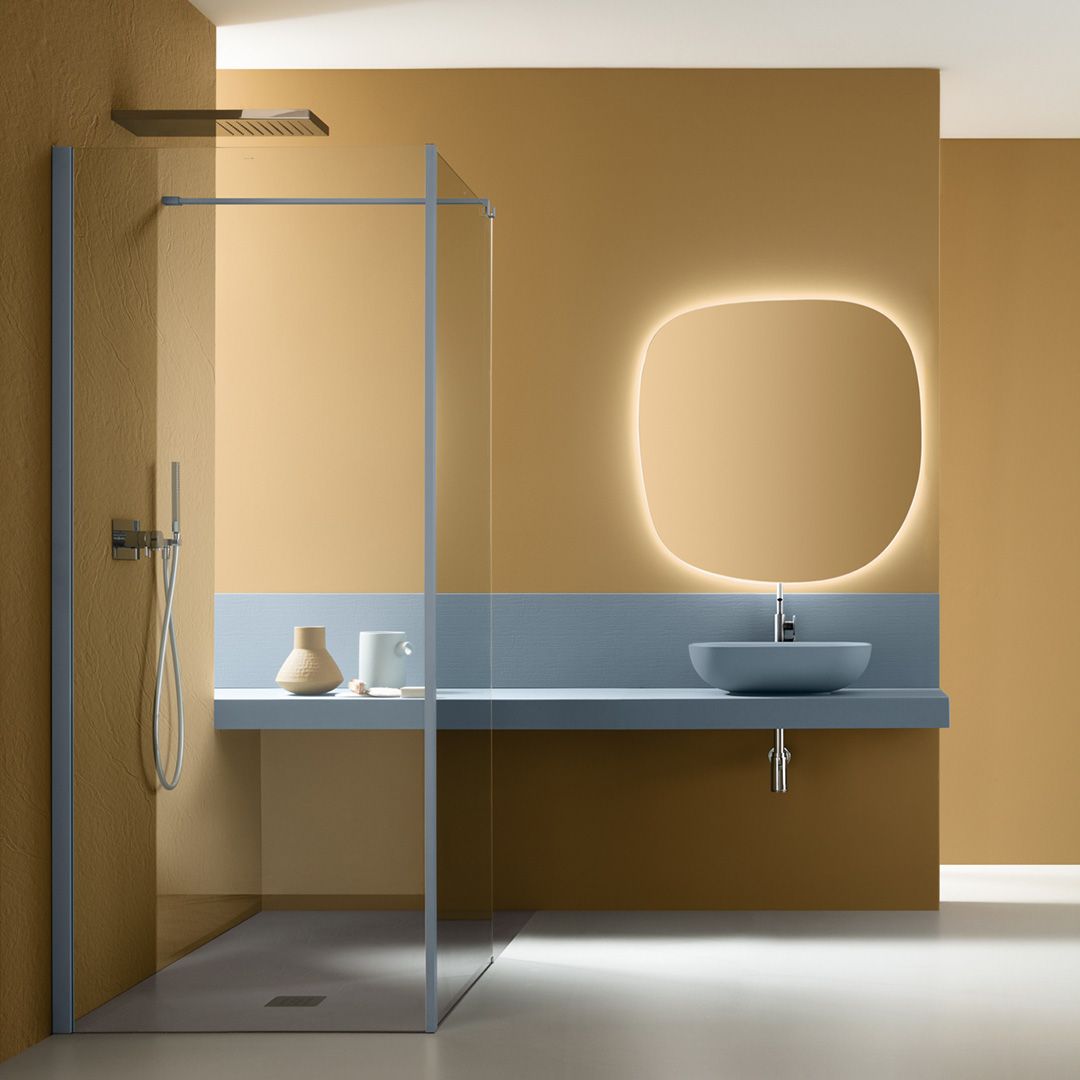 Bagno moderno con doccia in vetro, mobile lavabo sospeso, specchio rotondo retroilluminato e pareti beige.
