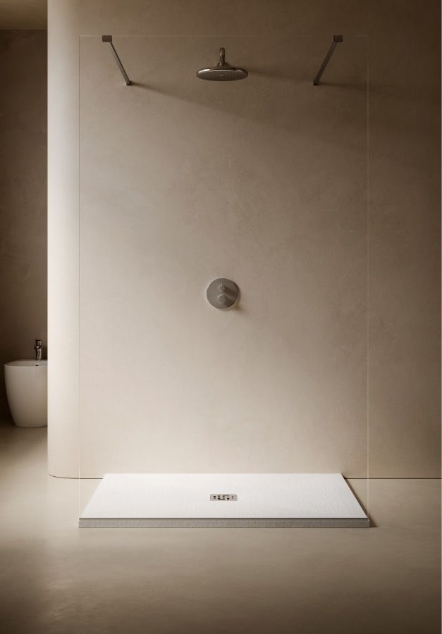 Box doccia minimalista beige con panca bianca e soffione a soffitto in un bagno.