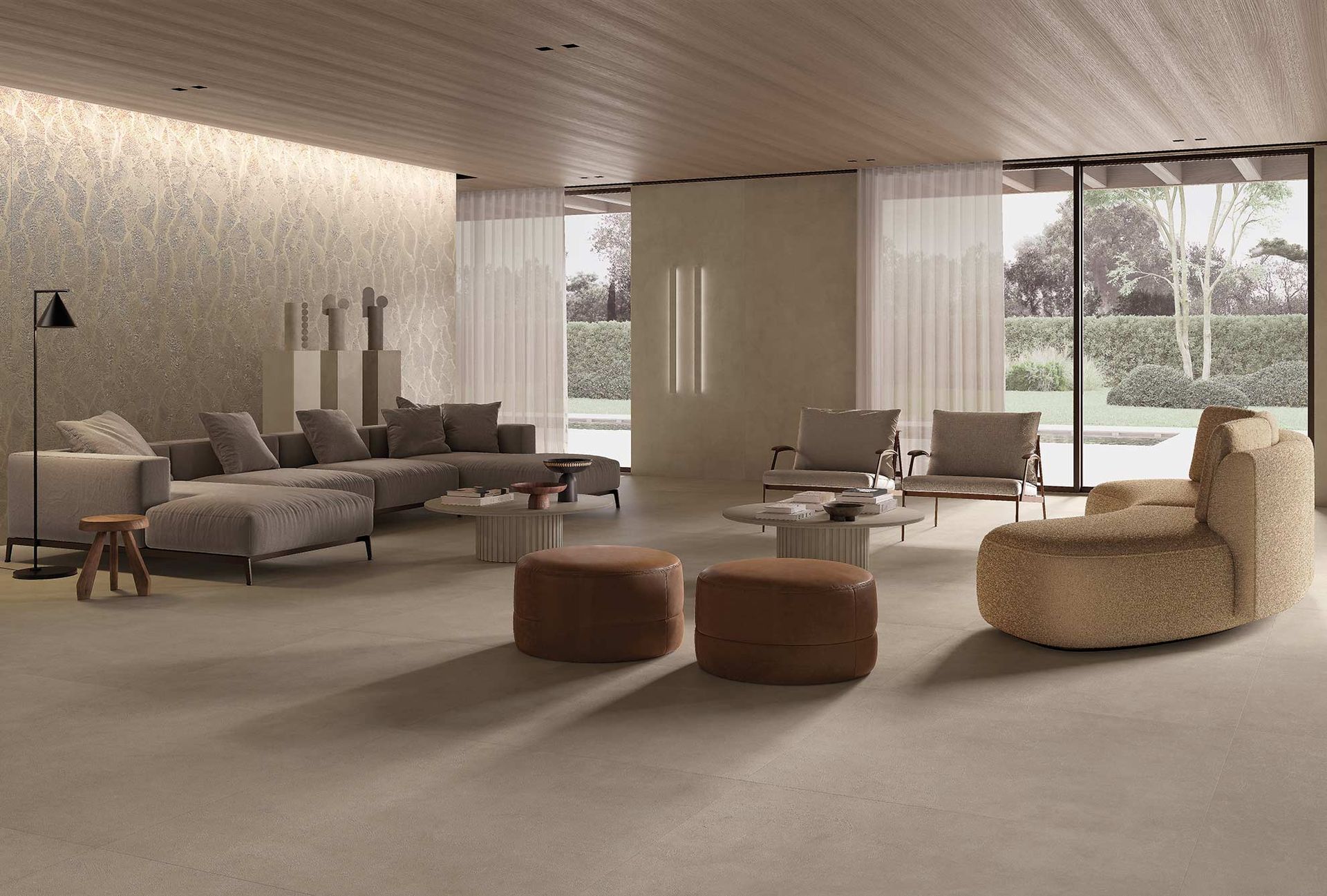 Soggiorno moderno con divano grigio, poltrone beige, pouf rotondi e finestre a tutta altezza.