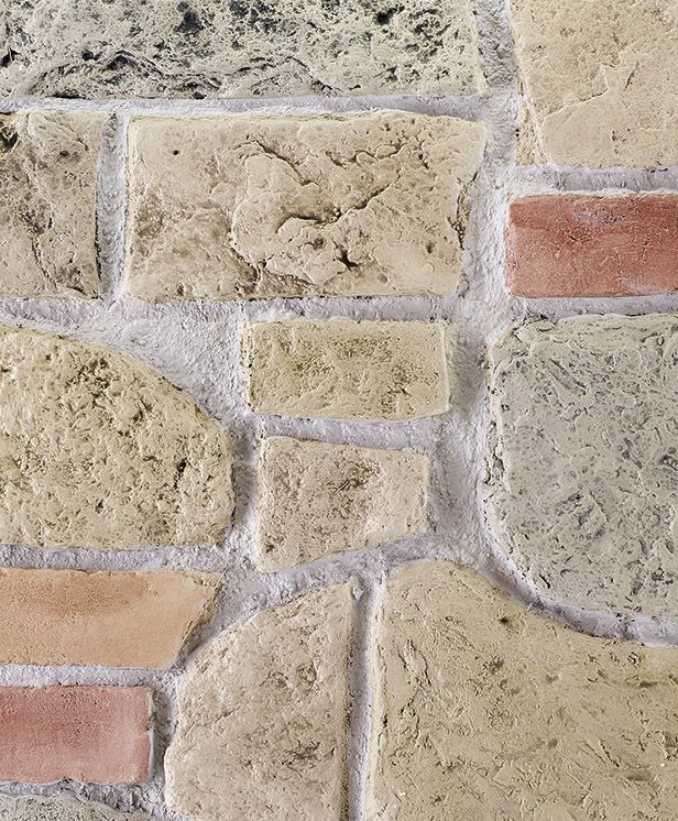 Primo piano di un muro in pietra beige con blocchi irregolari e leggere linee di malta.