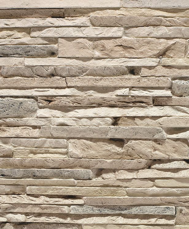 Primo piano di un muro in pietra beige a secco con texture rettangolari sovrapposte.