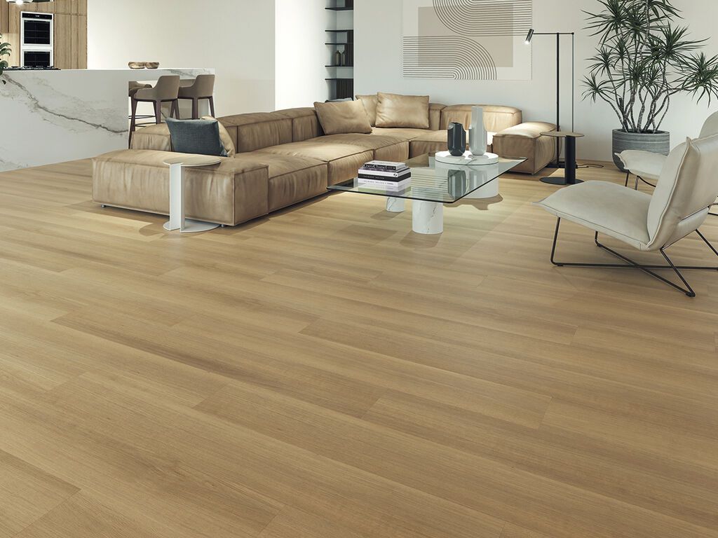 Soggiorno moderno con pavimento in legno chiaro, divano componibile beige, tavolino da caffè in vetro e grande pianta in vaso.