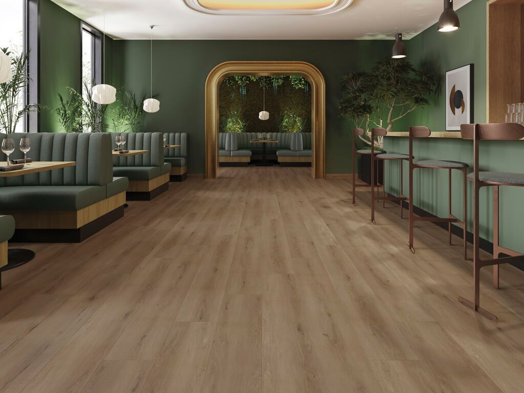 Elegante salone vuoto con pareti verdi, pavimento in legno, sedute color verde acqua e un bancone bar sul lato destro.