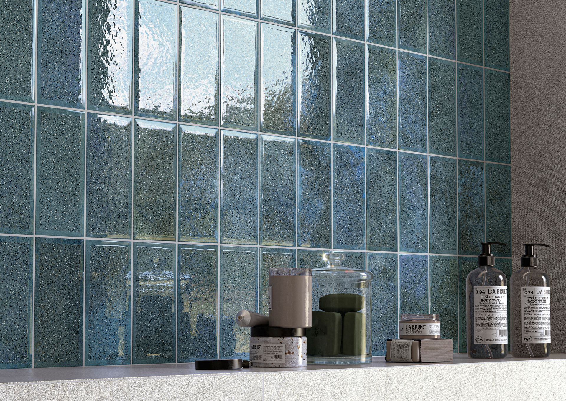 Mensola da bagno in piastrelle di vetro blu con candele, barattoli e dispenser di sapone.