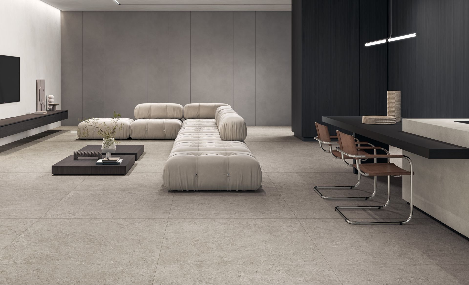 Soggiorno moderno e minimalista con divano modulare beige, tavolino basso e sgabelli da bar neri accanto a una scrivania a muro.