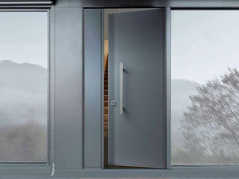 La moderna porta d'ingresso in vetro, leggermente aperta, rivela un interno accogliente tra ampie vetrate.