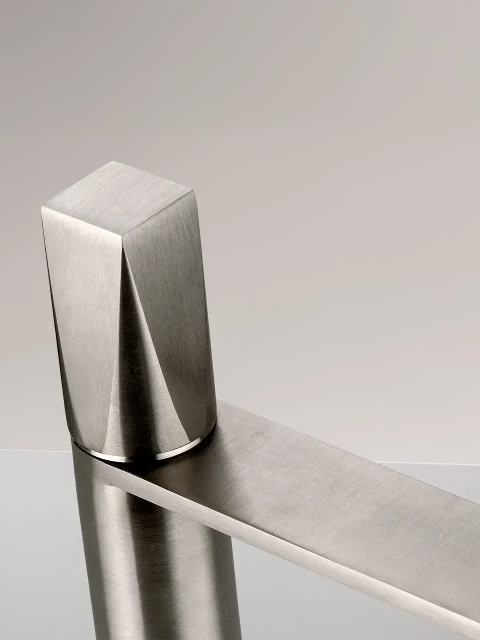 Montante di ringhiera moderno in acciaio inox con barra orizzontale su sfondo chiaro.