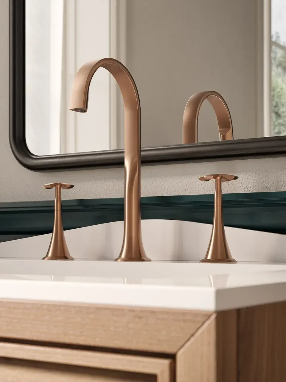 Rubinetto da bagno color oro rosa e due dispenser di sapone coordinati su un lavabo bianco con specchio.