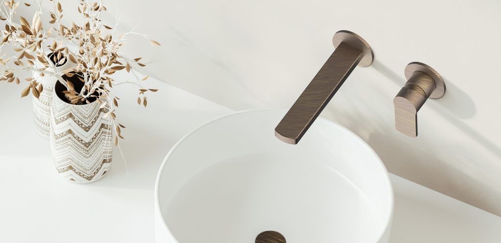 Lavabo bianco con rubinetto nero opaco, accanto a un piccolo vaso di fiori secchi su un piano d'appoggio chiaro.
