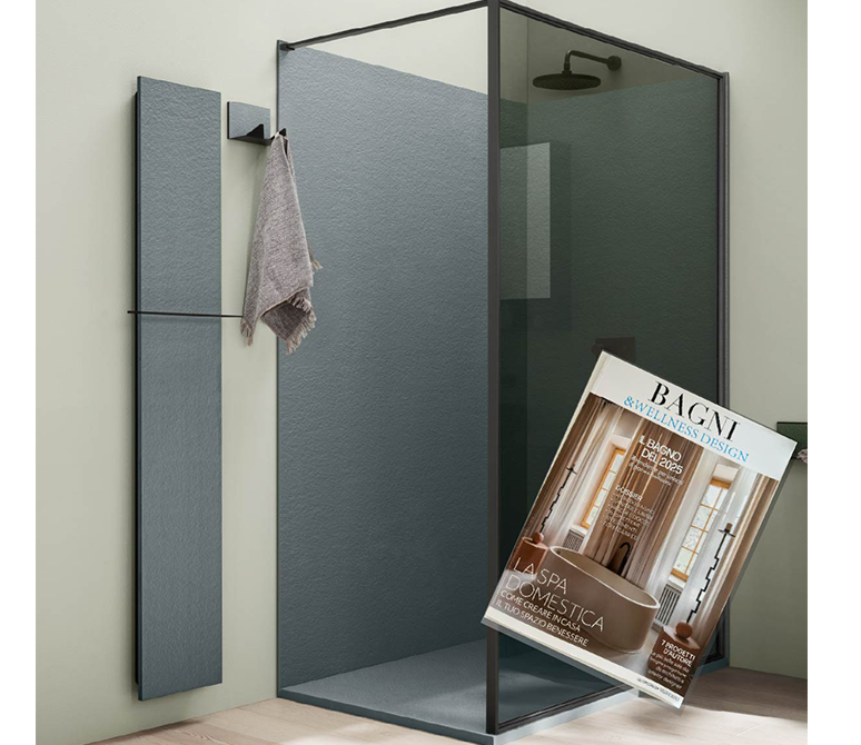 Bagno moderno con box doccia in vetro, asciugamano e rivista su sgabello.