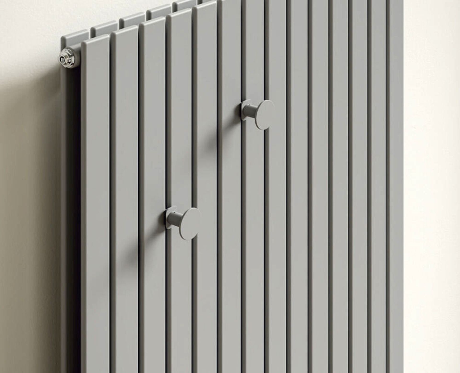 Radiatore verticale grigio con due manopole rotonde su una parete chiara