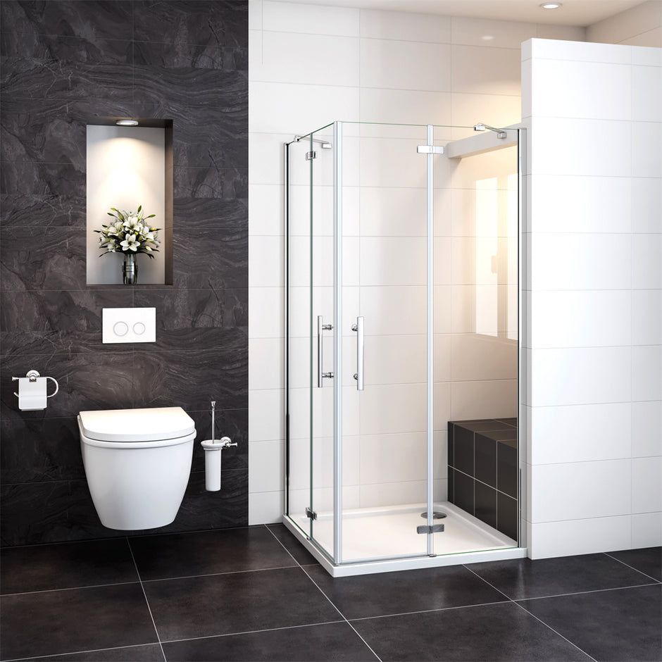 Bagno moderno con WC sospeso, doccia in vetro, pavimento in piastrelle scure e mensola incassata con fiori.