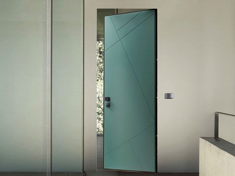 Interno moderno con una porta color verde acqua leggermente aperta in un corridoio minimalista.