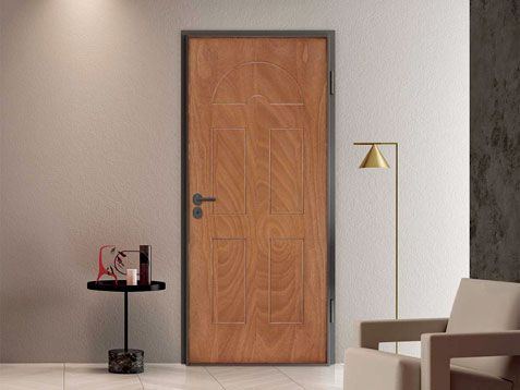 Stanza minimalista con porta in legno, tavolino, lampada da terra e sedia beige.