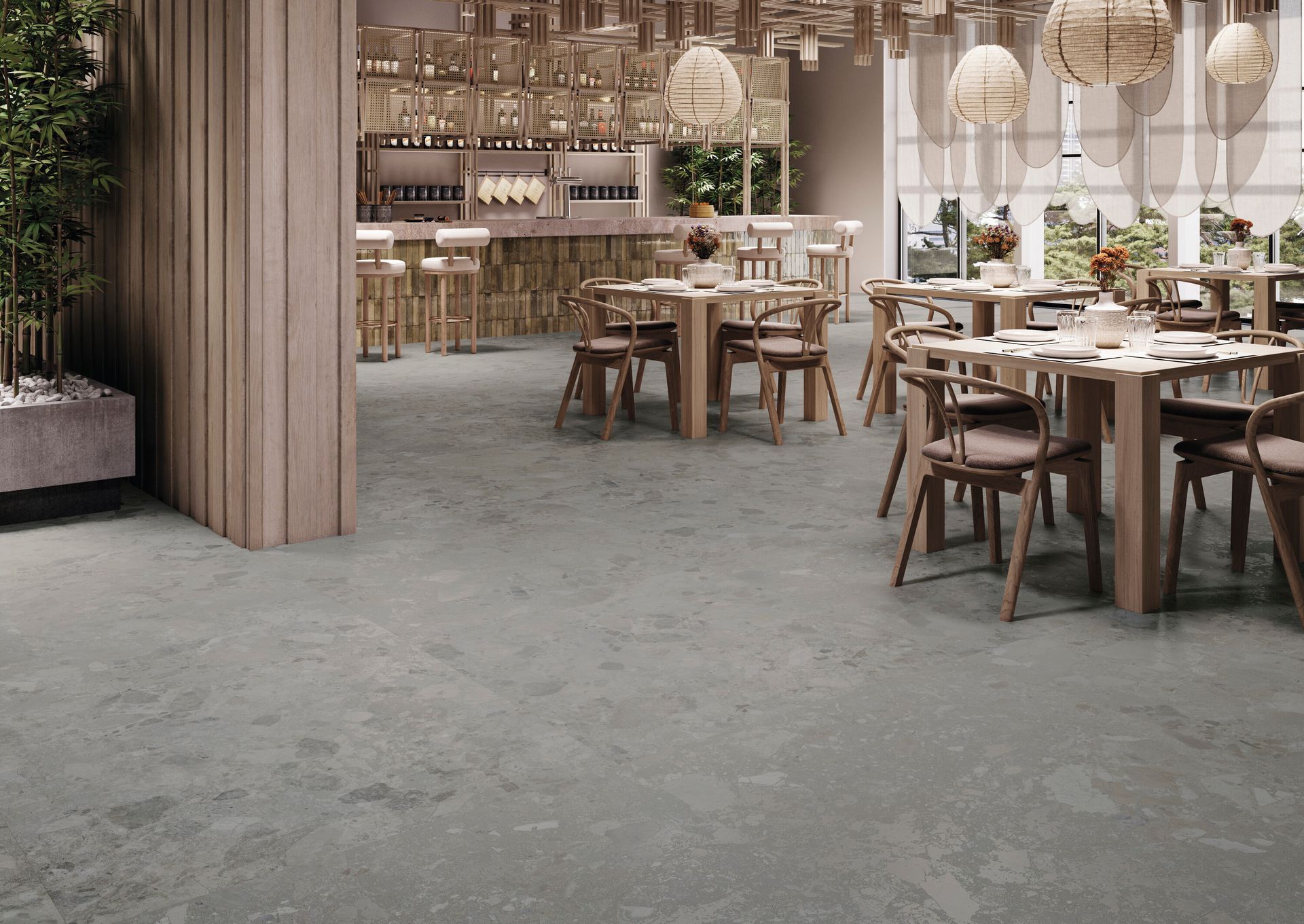 Interni moderni di un ristorante con tavoli in legno, lampade a sospensione e pavimento in pietra grigia.