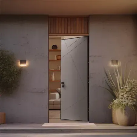 Ingresso moderno di colore grigio con porta parzialmente aperta, scaffali interni dai toni caldi, applique e composizione di piante in vaso.