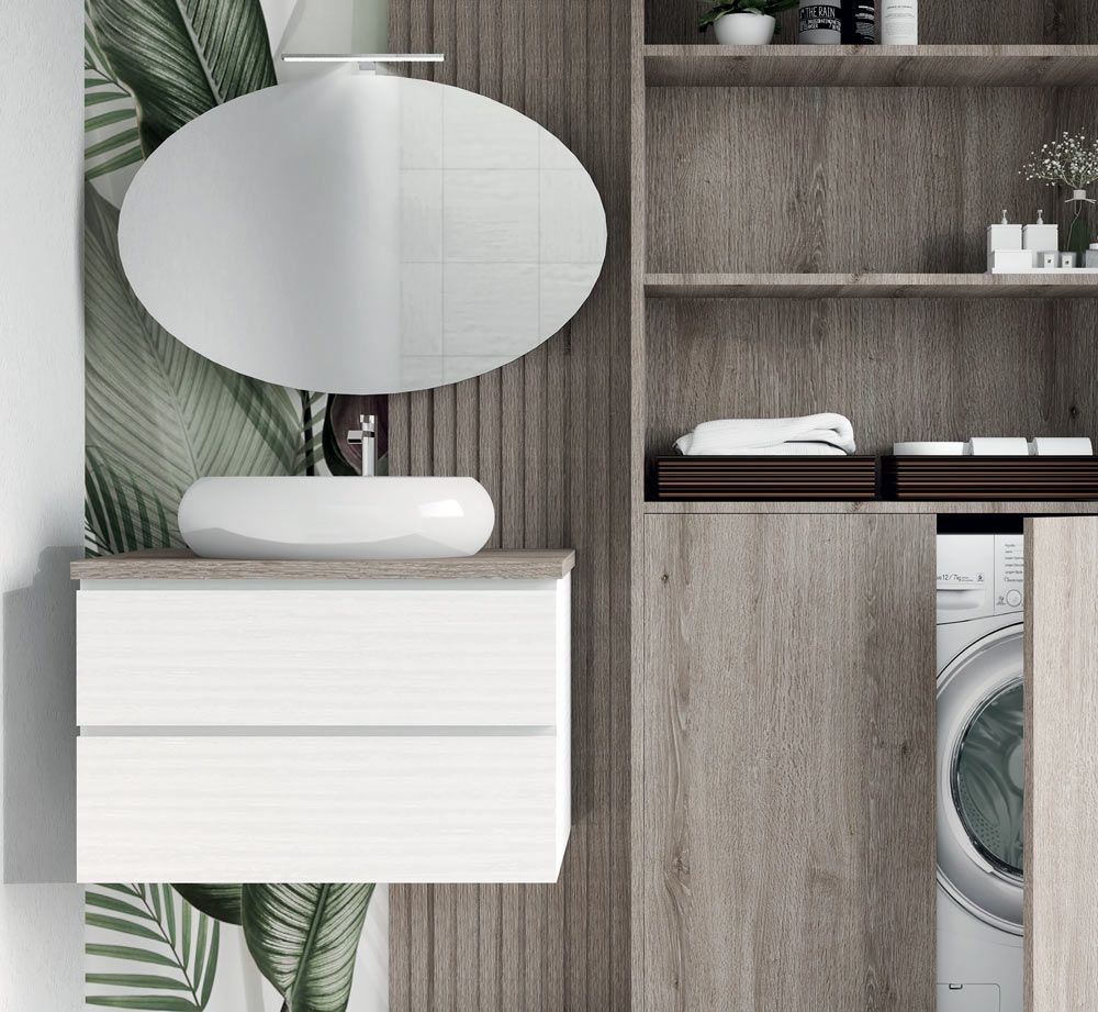 Mobile bagno moderno con specchio ovale, lavabo bianco e mensole in legno accanto a una lavatrice parzialmente a vista.