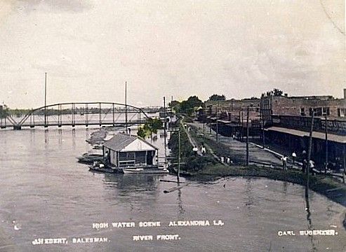 A black and white photo of a flooded city with a bridge in the background.