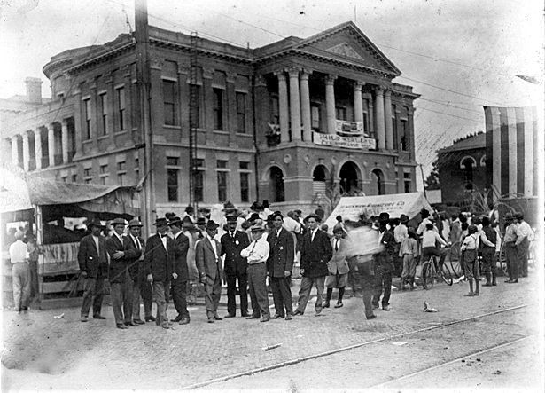 A group of men are standing in front of a large building.
