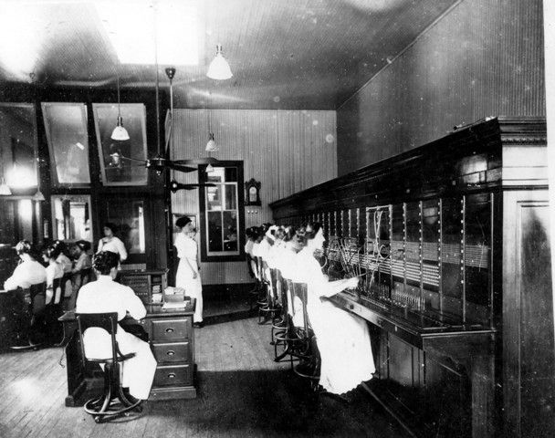A black and white photo of people working in a telephone booth